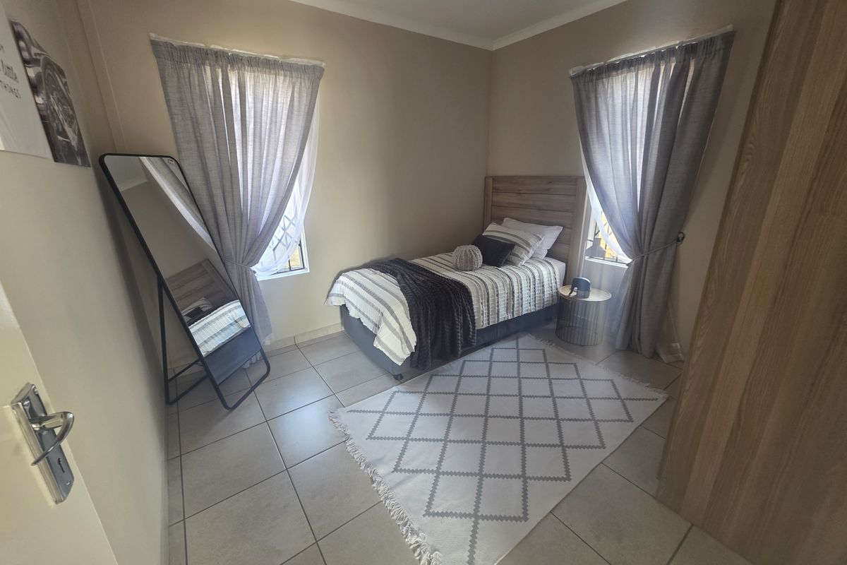 A well-maintained bedroom featuring neutral wall tones, tiled flooring, and a built-in cupboard, offering a clean and functional living space.