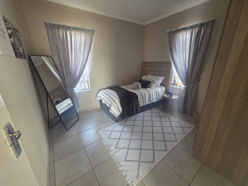 A well-maintained bedroom featuring neutral wall tones, tiled flooring, and a built-in cupboard, offering a clean and functional living space.