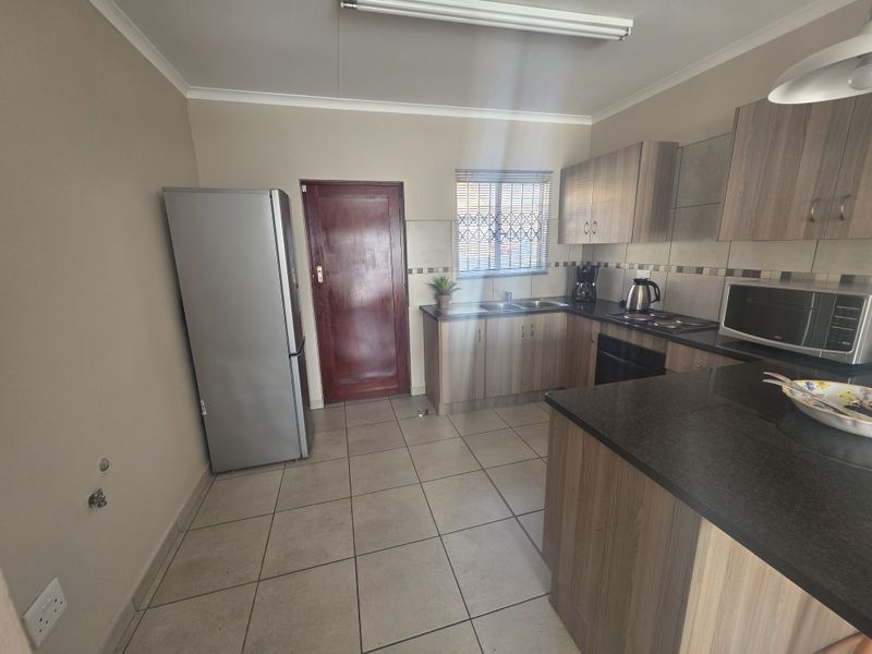 Functional kitchen featuring laminate cabinetry, granite countertops, tiled flooring, and a built-in oven with hob, providing a practical workspace for daily cooking.