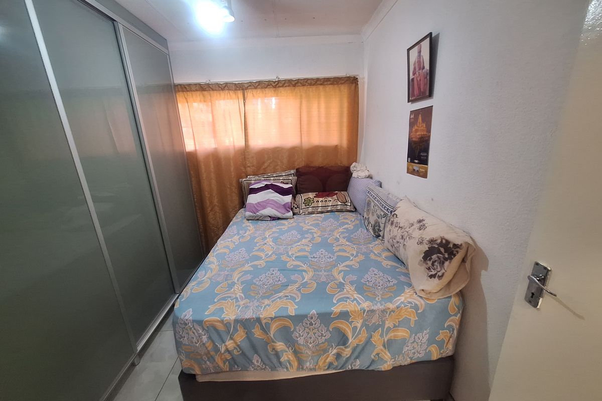 A compact bedroom featuring built-in sliding door cupboards and tiled flooring, providing functional storage space.