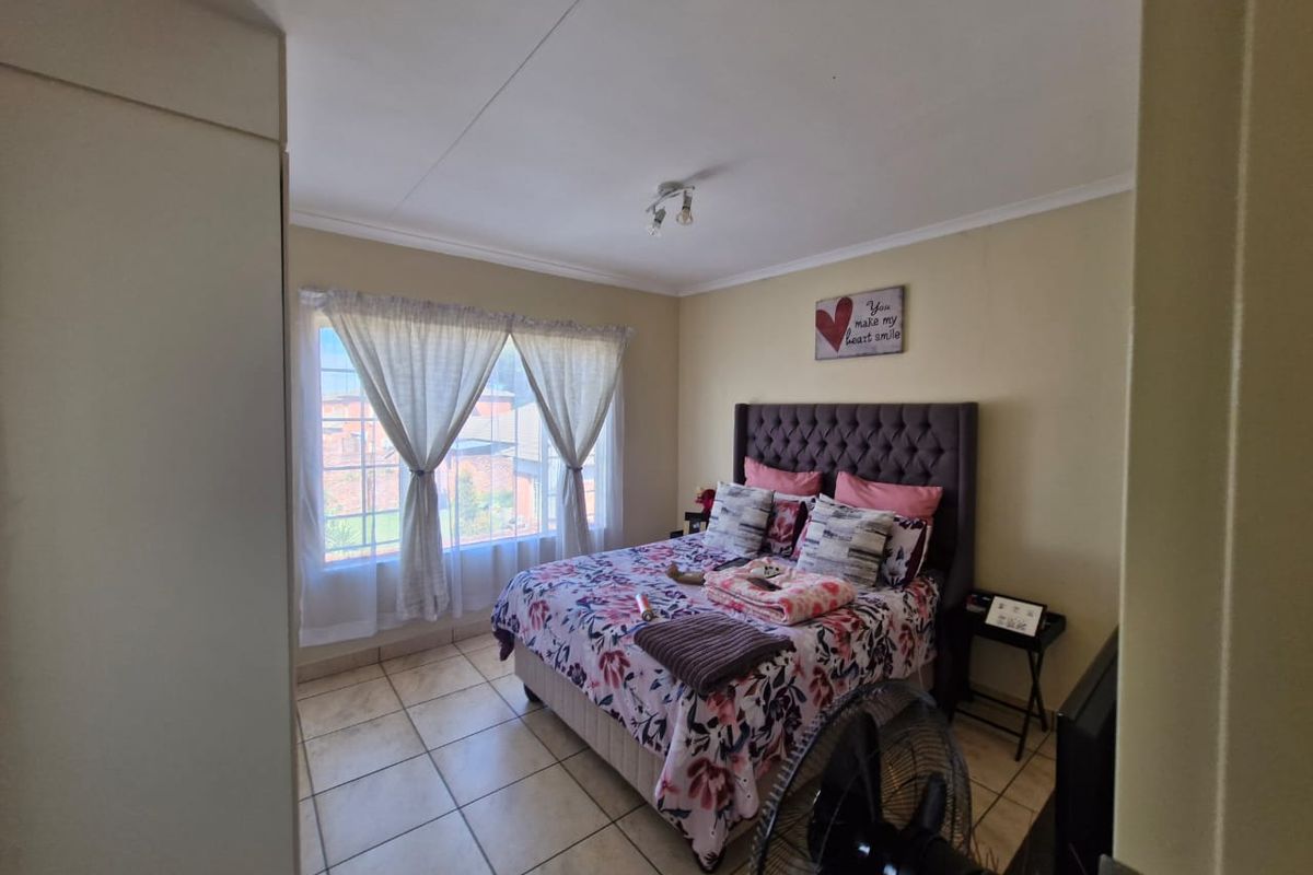 A bedroom featuring tiled flooring and a built-in wardrobe, offering a functional space with natural light from the window.
