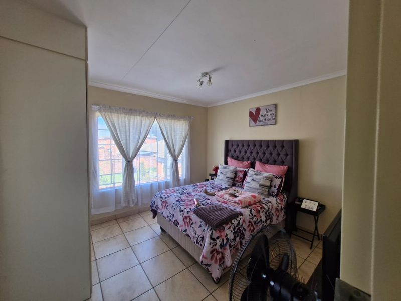 A bedroom featuring tiled flooring and a built-in wardrobe, offering a functional space with natural light from the window.