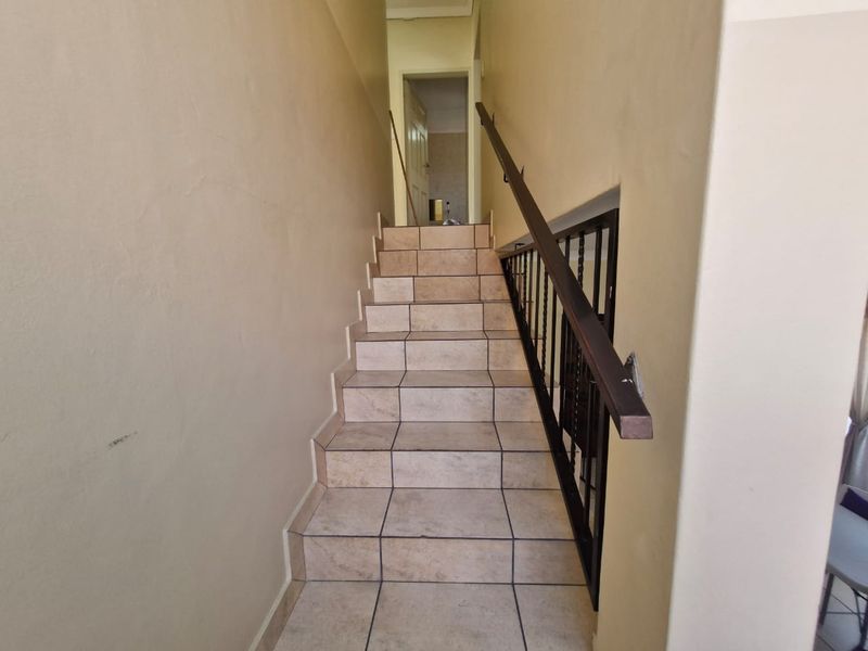 A functional staircase featuring tiled steps and a metal handrail, providing access between levels within the townhouse.