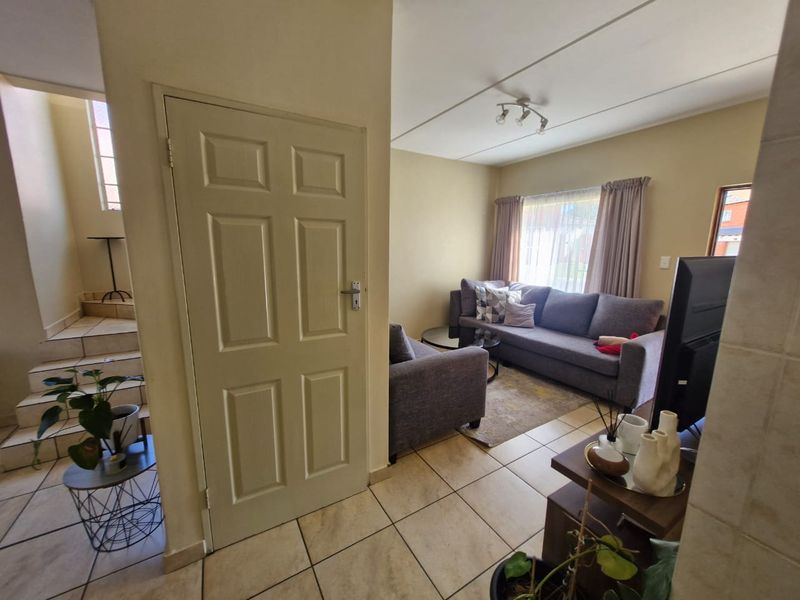 A living room area featuring tiled flooring, a staircase leading to the upper level, and neutral wall finishes.