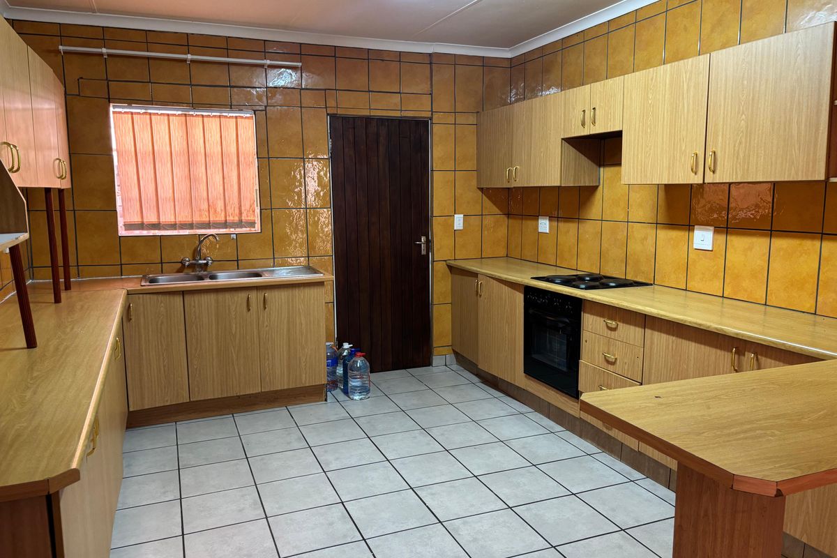 A functional kitchen featuring extensive built-in cabinetry, laminate countertops, a built-in oven with hob, and tiled surfaces throughout.