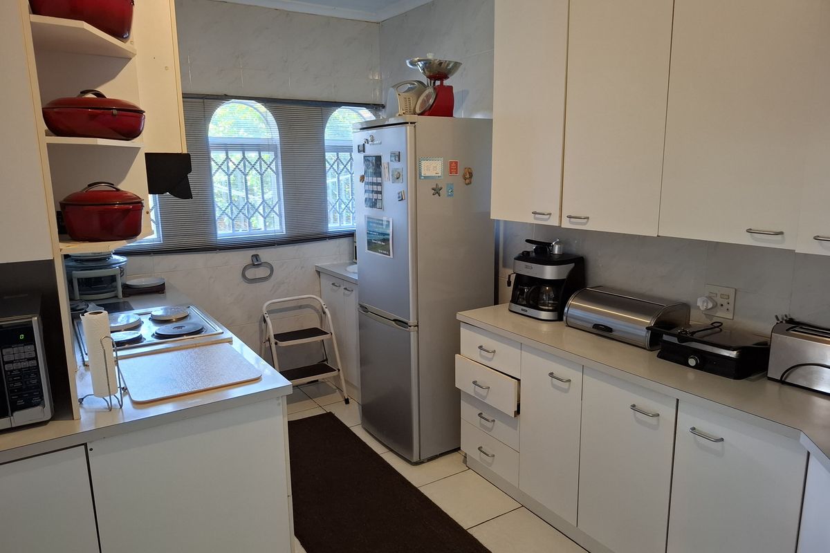 A functional kitchen featuring white cabinetry, tiled walls, built-in hob, and tiled flooring with a compact layout.