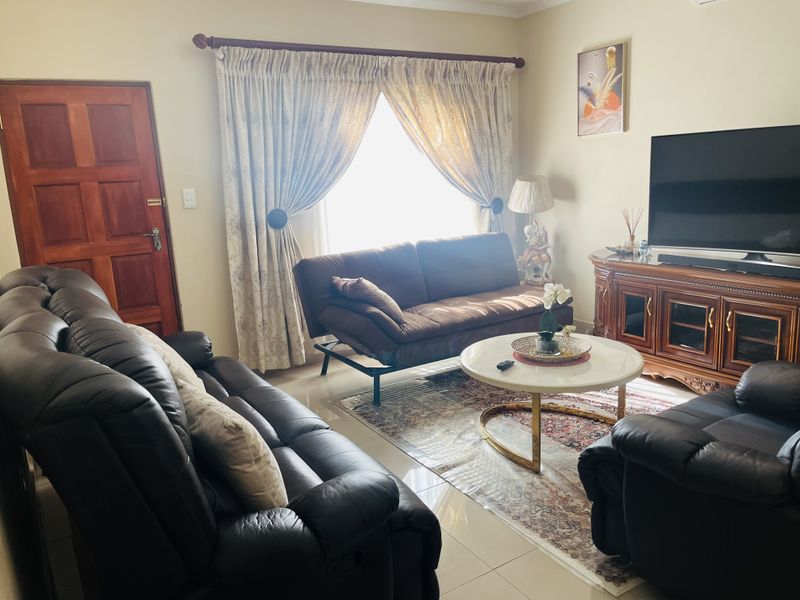 A comfortable living room featuring tiled flooring, a solid timber door, and an installed air conditioning unit.