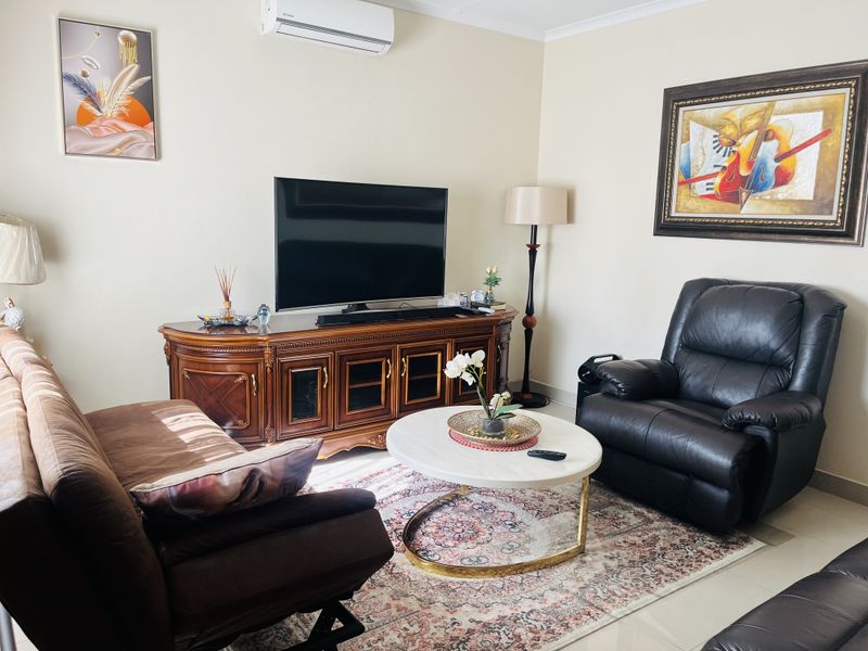 A comfortable living room featuring tiled flooring and a wall-mounted split-system air conditioner.