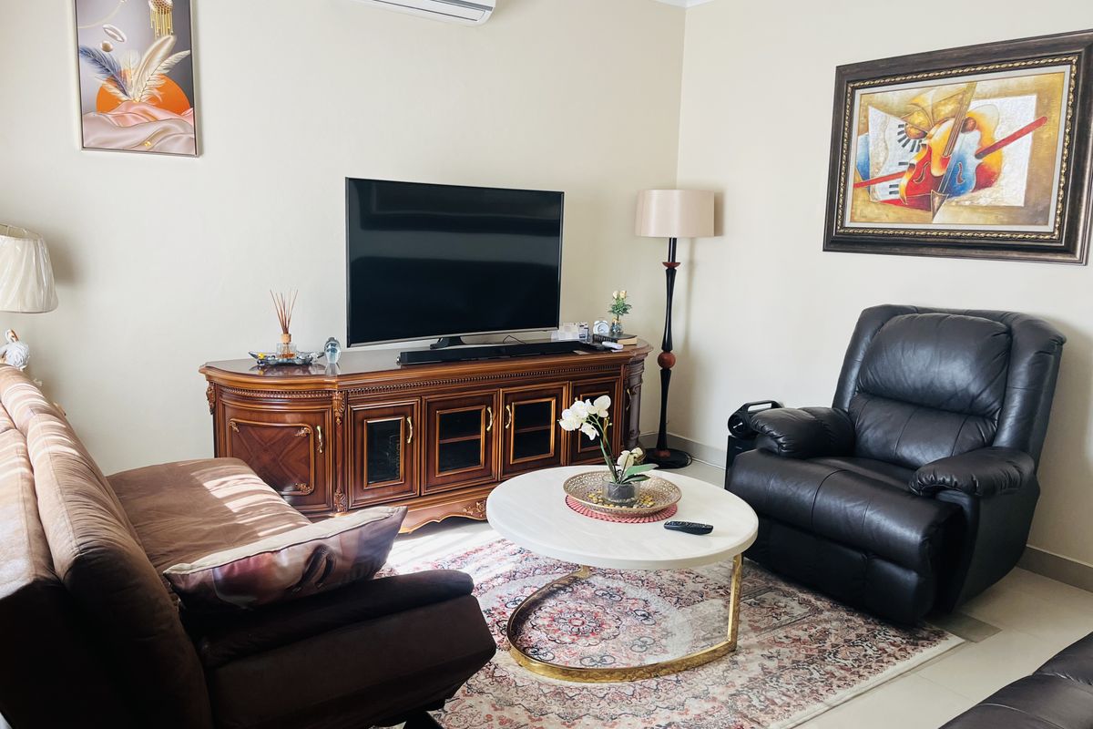 A comfortable living room featuring tiled flooring and a wall-mounted split-system air conditioner.