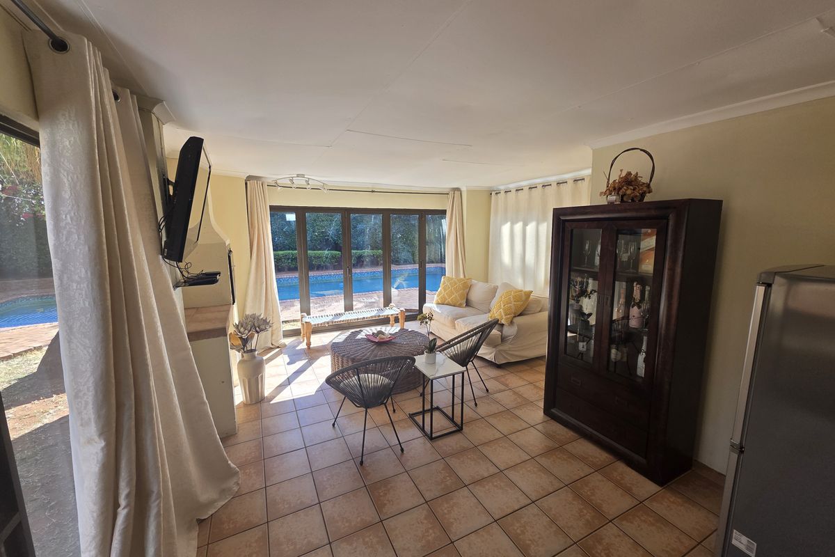 A bright living room featuring tiled flooring, a built-in fireplace, and large sliding glass doors providing direct access to the outdoor pool area.