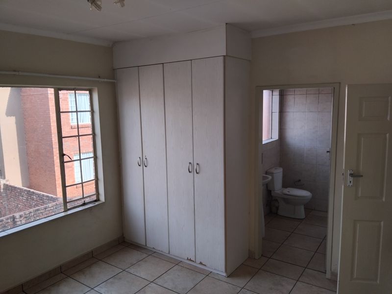 A bedroom featuring tiled flooring, a built-in wardrobe with minor wear, and an adjoining en-suite bathroom.