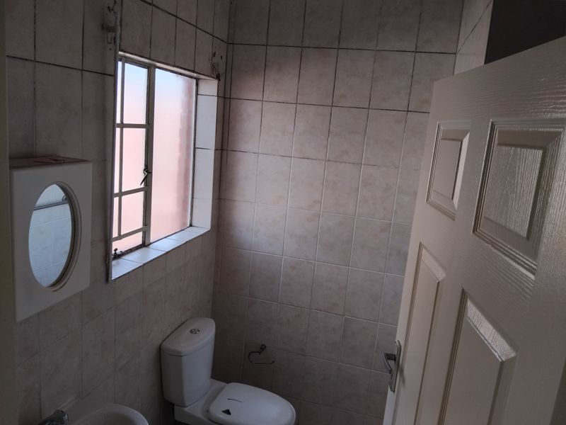 A compact bathroom featuring tiled walls, a toilet, and a wall-mounted mirror cabinet. The space is ready for modernization and cosmetic updates.