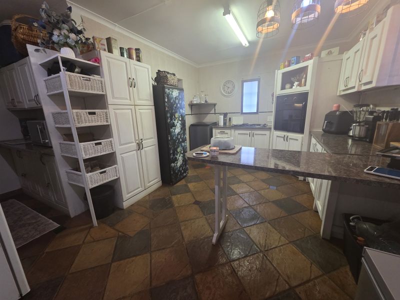 A functional kitchen featuring built-in cabinetry, granite countertops, a built-in oven, and durable tiled flooring.