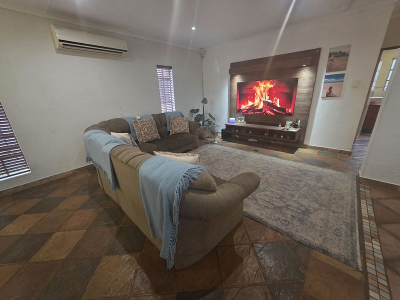 A comfortable living room featuring tiled flooring, a timber feature wall, and a wall-mounted split-system air conditioner.