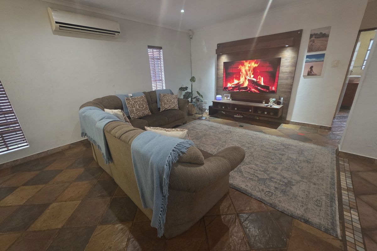 A comfortable living room featuring tiled flooring, a timber feature wall, and a wall-mounted split-system air conditioner.