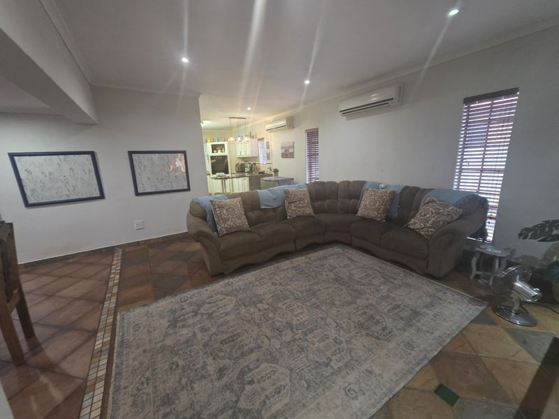 Open-plan living area featuring tiled flooring, recessed lighting, and dual split-system air conditioning units, with a view through to the kitchen area.