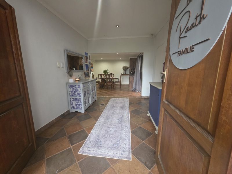 Welcoming entrance hall featuring terracotta floor tiles and recessed lighting, leading through to an open-plan dining area.