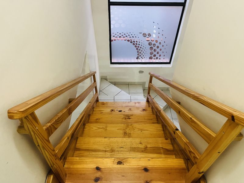 A wooden staircase with matching handrails leading to a landing area featuring a decorative frosted glass window.