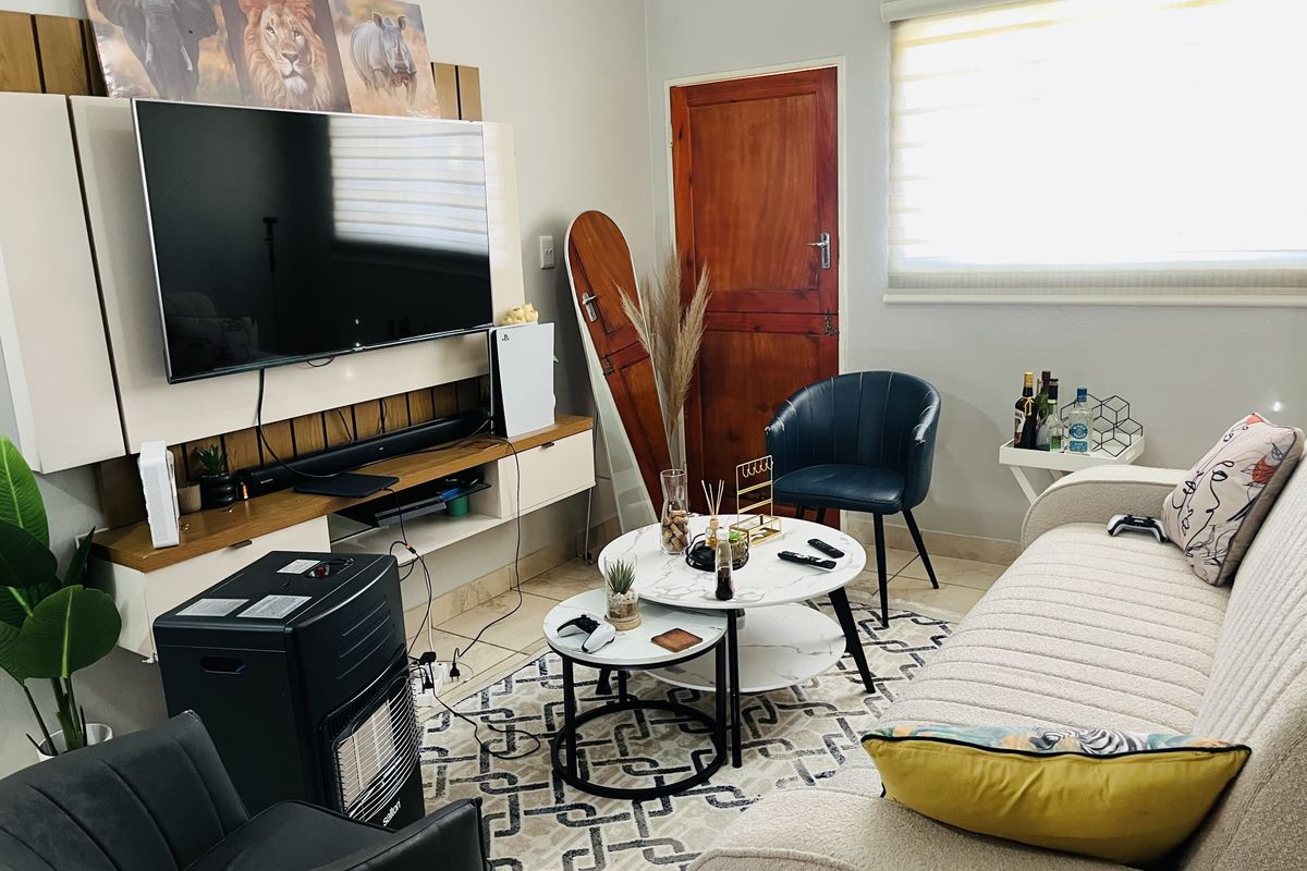 A cozy living room featuring a built-in media console, tiled flooring, and a large window with fitted blinds.