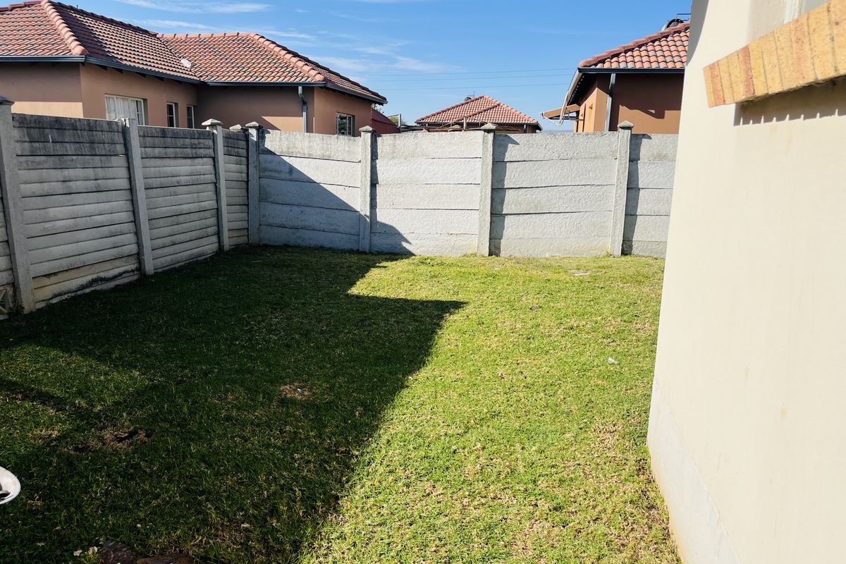 A private rear garden area featuring a lawn and enclosed by precast concrete boundary walls, providing a secure outdoor space for the townhouse.