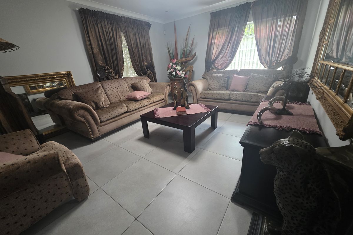 A spacious living room featuring large format floor tiles, neutral wall finishes, and ample natural light through multiple windows.