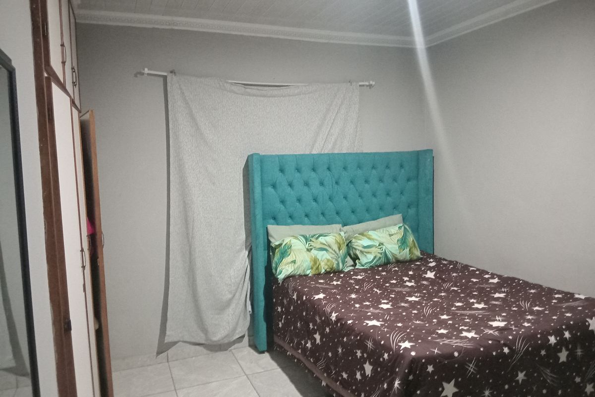 A bedroom featuring built-in cupboards, tiled flooring, and a tongue and groove ceiling.