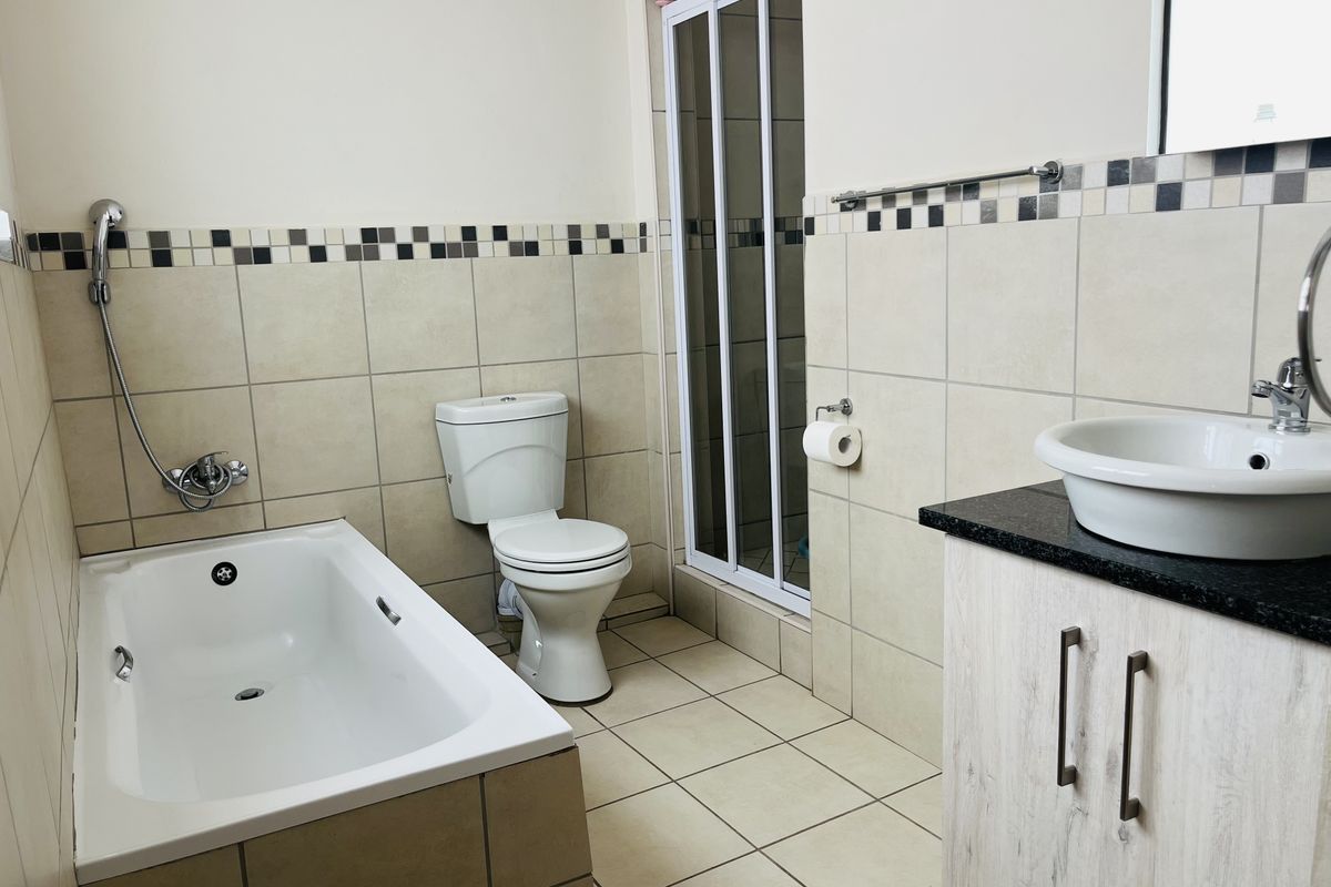 A functional bathroom featuring a built-in bathtub, separate shower enclosure, toilet, and a vanity with a countertop basin.