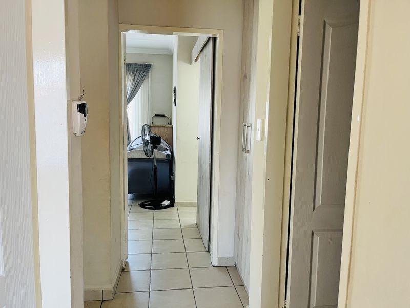A functional hallway featuring tiled flooring, built-in cabinetry, and an integrated alarm system panel, providing access to adjacent rooms.