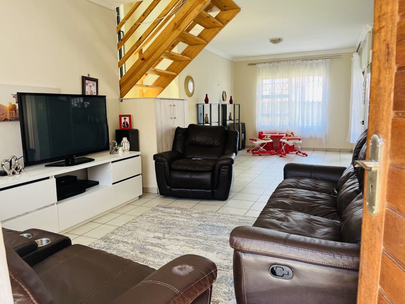 Open plan living area featuring tiled flooring and a wooden staircase leading to the upper level.