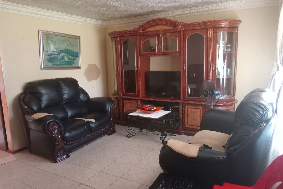 A living room featuring tiled flooring and decorative ceiling tiles, providing a functional space with built-in cabinetry.