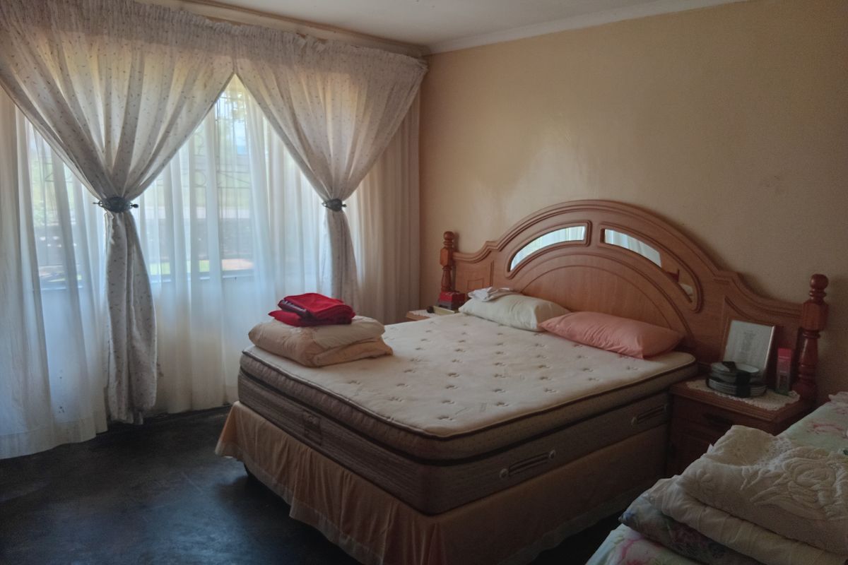 A bedroom featuring a large window with curtains and neutral wall finishes.