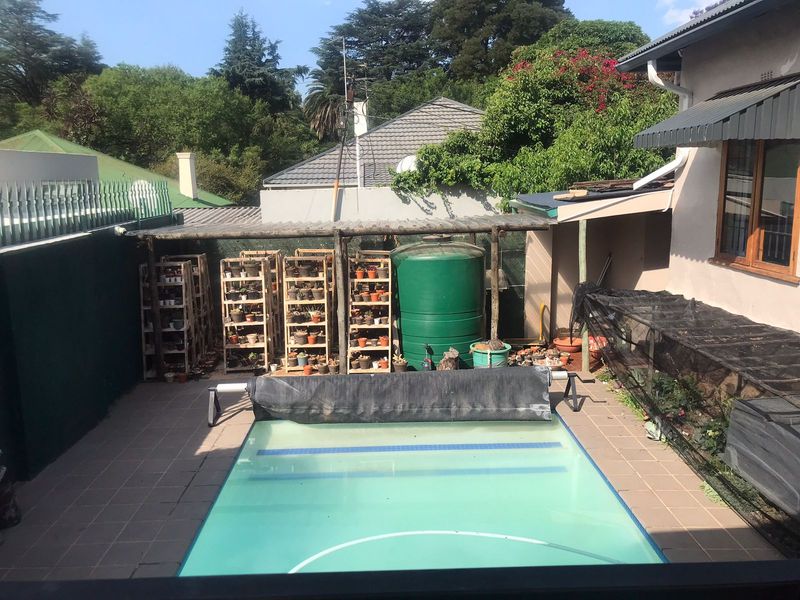 Outdoor pool area featuring a tiled patio, timber pergola, and a water storage tank, providing a functional space for outdoor recreation.