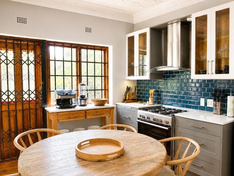 A well-appointed kitchen featuring dark subway tile backsplash, stone countertops, gas stove with extractor, and elegant glass-fronted cabinetry with decorative ceiling detailing.