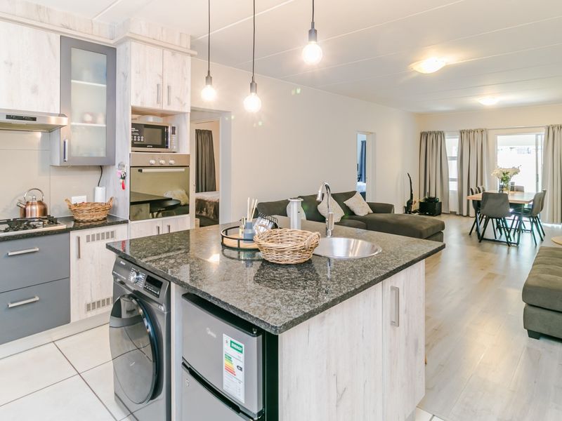 Modern open-plan living area featuring a well-equipped kitchen with granite island, built-in appliances, and seamless flow into the dining and lounge spaces.