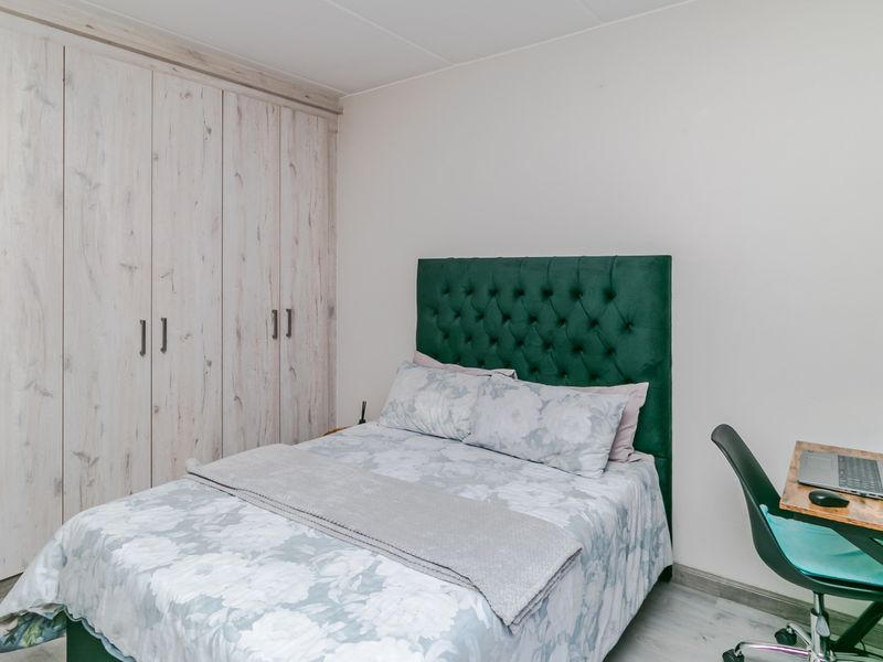 A well-maintained bedroom featuring light wood-look built-in cupboards and modern laminate flooring.
