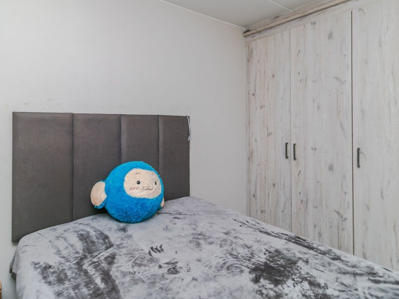 A bedroom featuring a built-in wardrobe with a light wood-grain finish and a neutral wall palette.