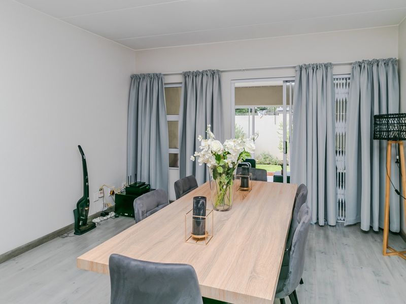 A bright dining area featuring light-toned laminate flooring and a large sliding glass door providing access to the outdoor space.