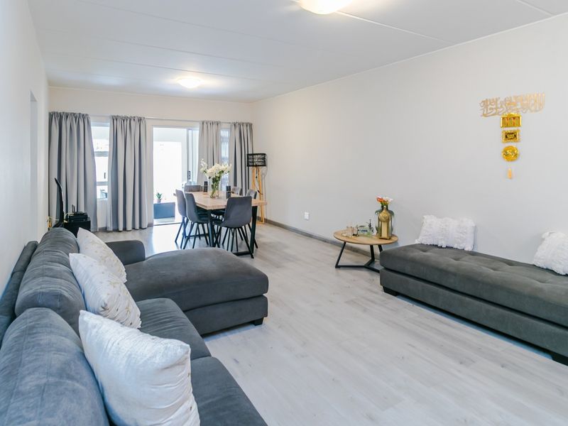 Spacious open-plan living and dining area featuring light-toned laminate flooring and direct access to an outdoor patio through sliding glass doors.