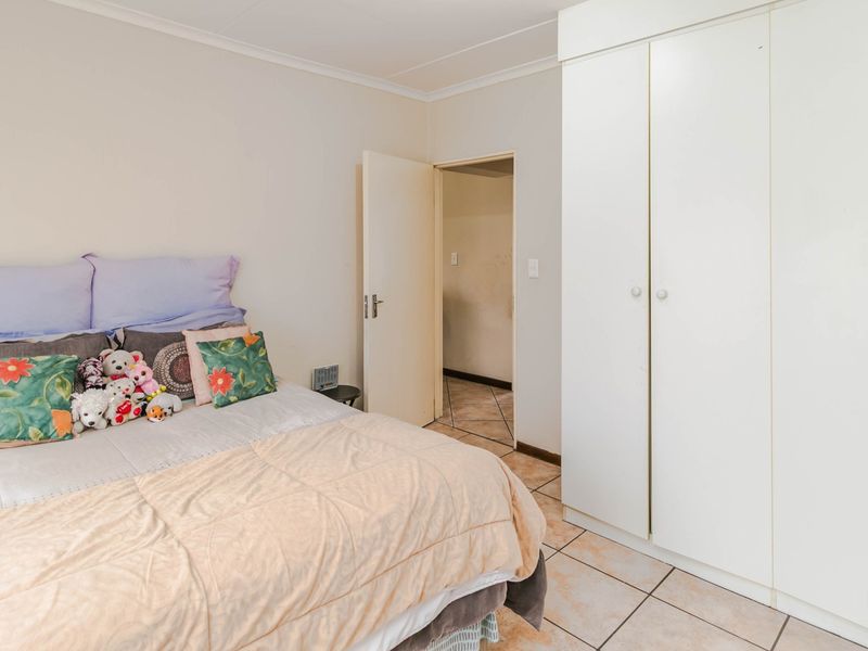 A bedroom featuring tiled flooring, a built-in wardrobe, and neutral wall finishes, providing a functional space with potential for modern updates.