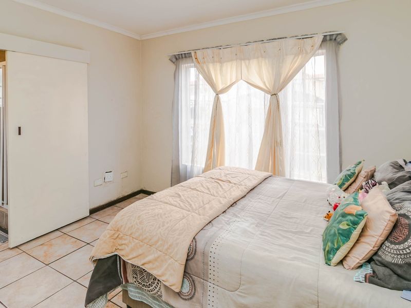 A bedroom featuring tiled flooring and an integrated en-suite bathroom with a shower enclosure and vanity.