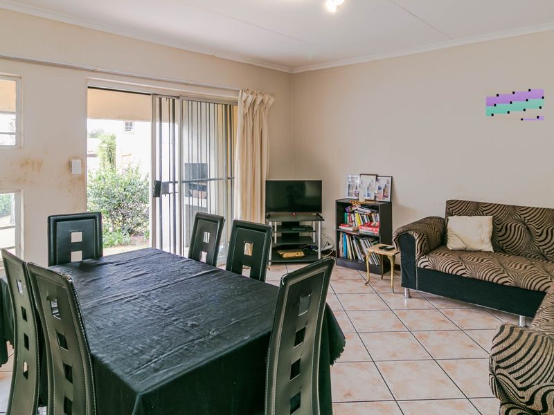 Open plan living and dining area featuring tiled flooring and a sliding glass door leading to an outdoor patio space.