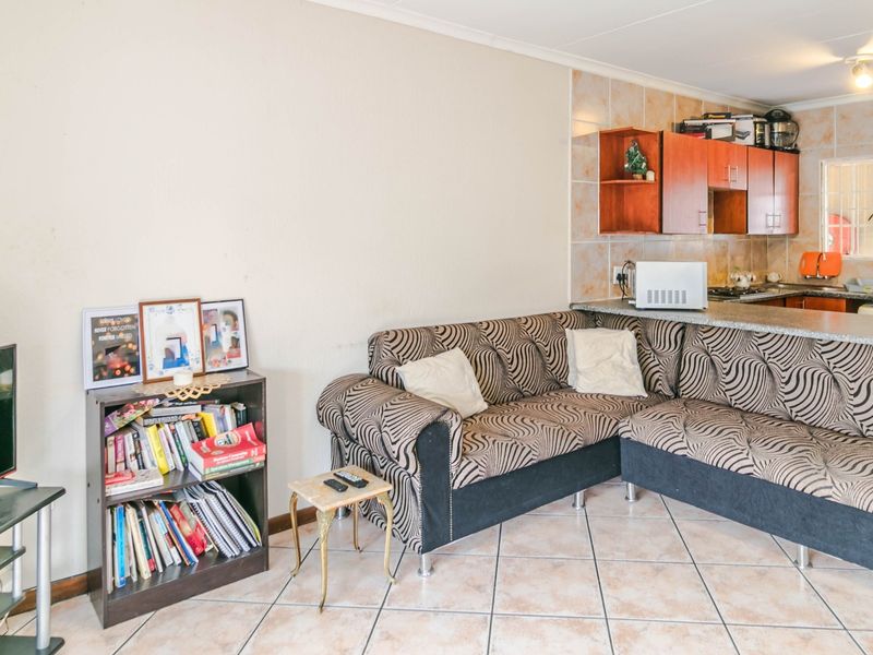 Open plan living area featuring tiled flooring and a functional kitchen with granite countertops and breakfast bar seating.