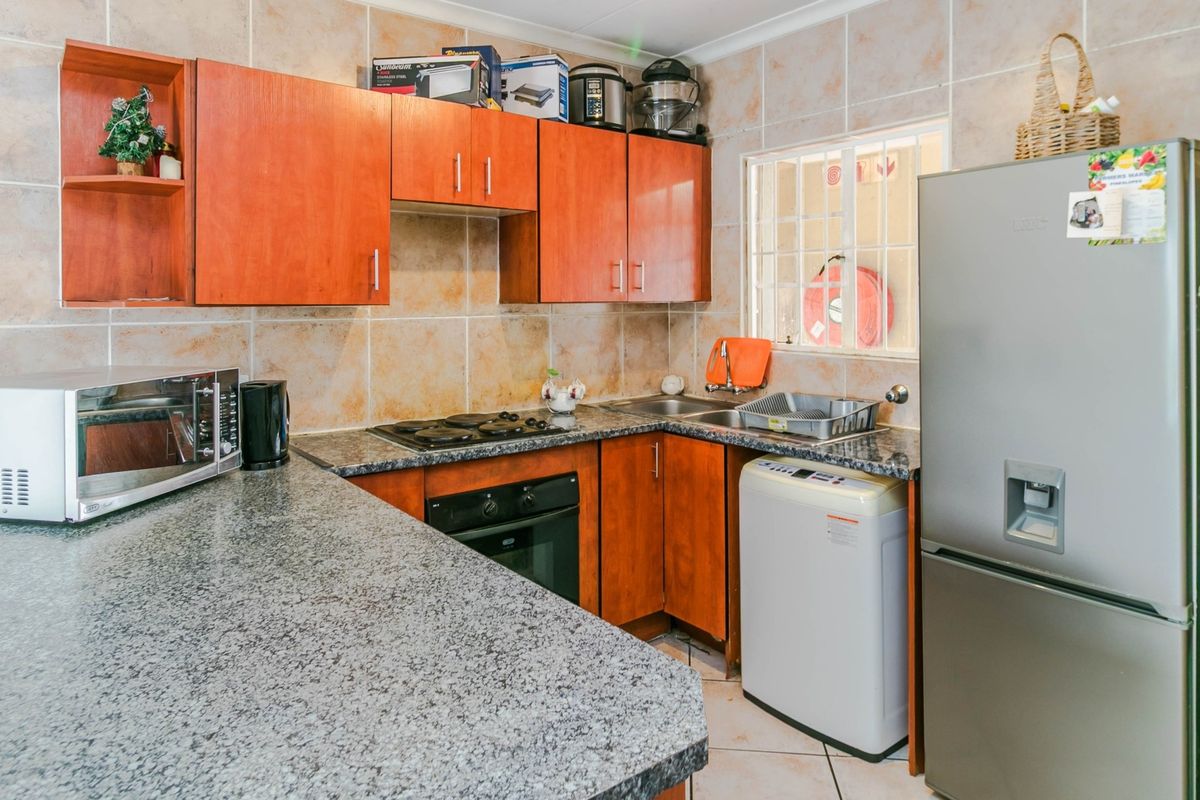 A functional kitchen featuring granite countertops, built-in cabinetry, a hob, an oven, and a double sink with tiled wall finishes.