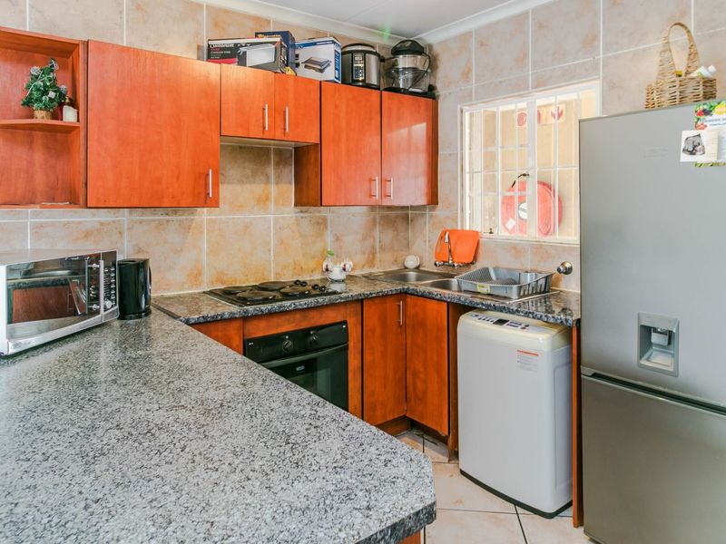 A functional kitchen featuring granite countertops, built-in cabinetry, a hob, an oven, and a double sink with tiled wall finishes.