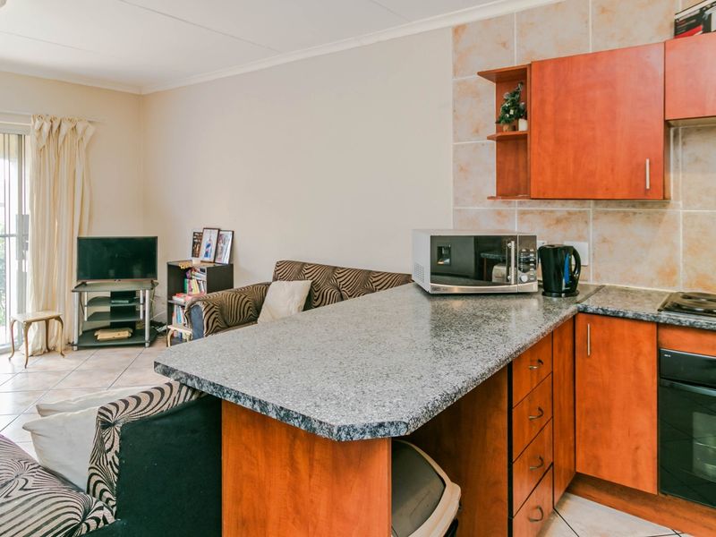 Open-plan living area featuring a kitchen with granite countertops, built-in oven, and hob, flowing into a lounge space with access to a sliding door.
