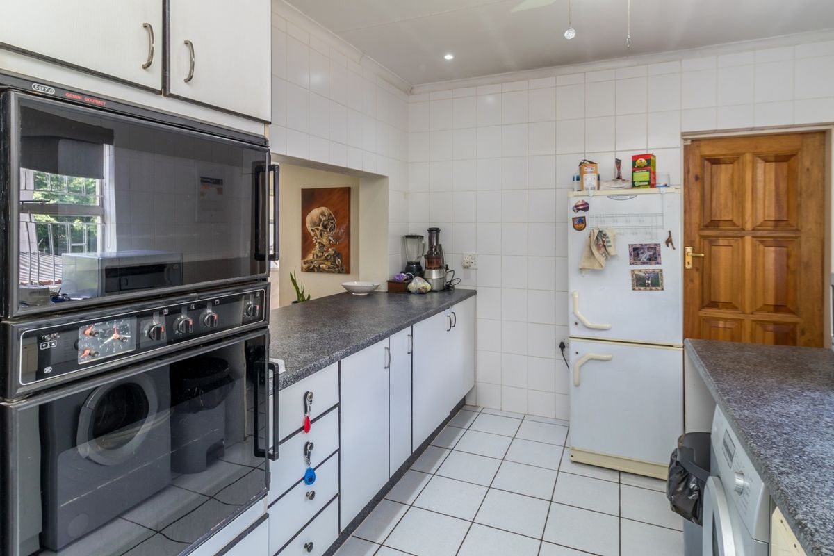 A functional kitchen featuring built-in oven, laminate countertops, tiled backsplash, and tiled flooring, offering a practical layout with ample storage cabinetry.