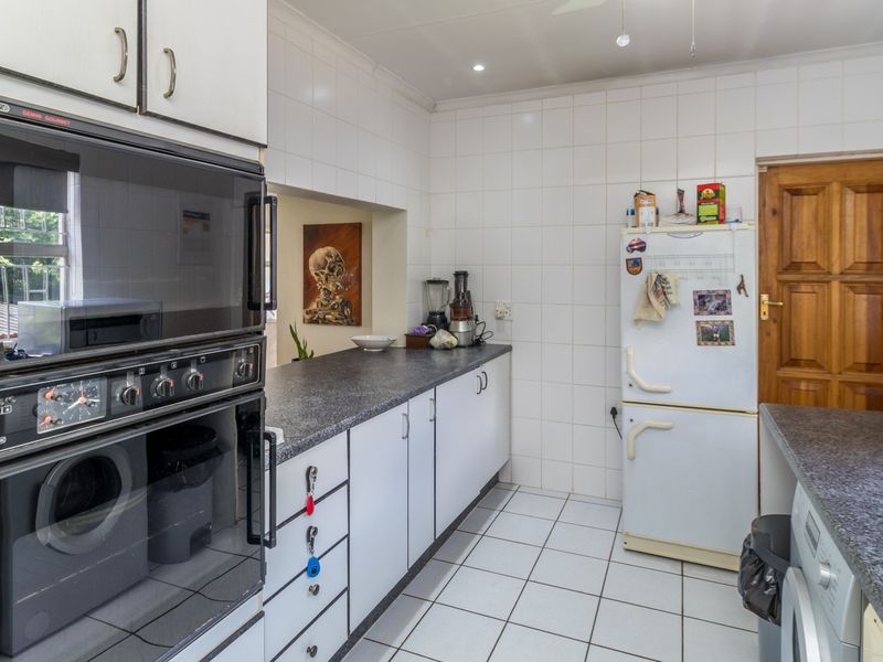 A functional kitchen featuring built-in oven, laminate countertops, tiled backsplash, and tiled flooring, offering a practical layout with ample storage cabinetry.