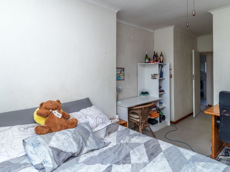 A bedroom featuring neutral walls with visible signs of wear and staining, coving, and access to an adjoining room.