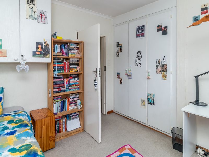 A functional bedroom featuring built-in cupboards, overhead storage cabinets, and carpeted flooring, providing practical storage solutions within the living space.
