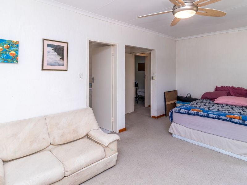 A functional bedroom featuring carpeted flooring, a ceiling fan, and direct access to adjacent rooms.